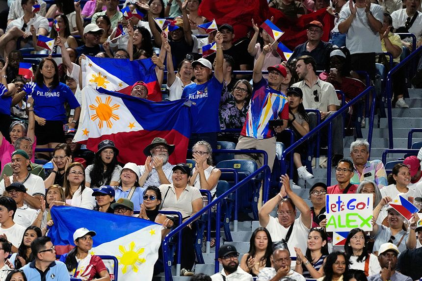 A crowded stadium filled with cheering fans waving Philippine flags and holding banners in support of Alex Eala.